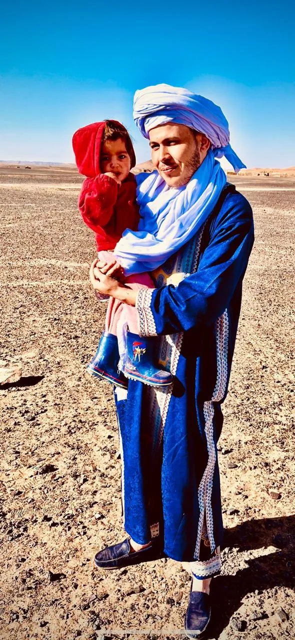 Abdou, founder of Oasis Roads, in a blue gandoura and turban in the desert