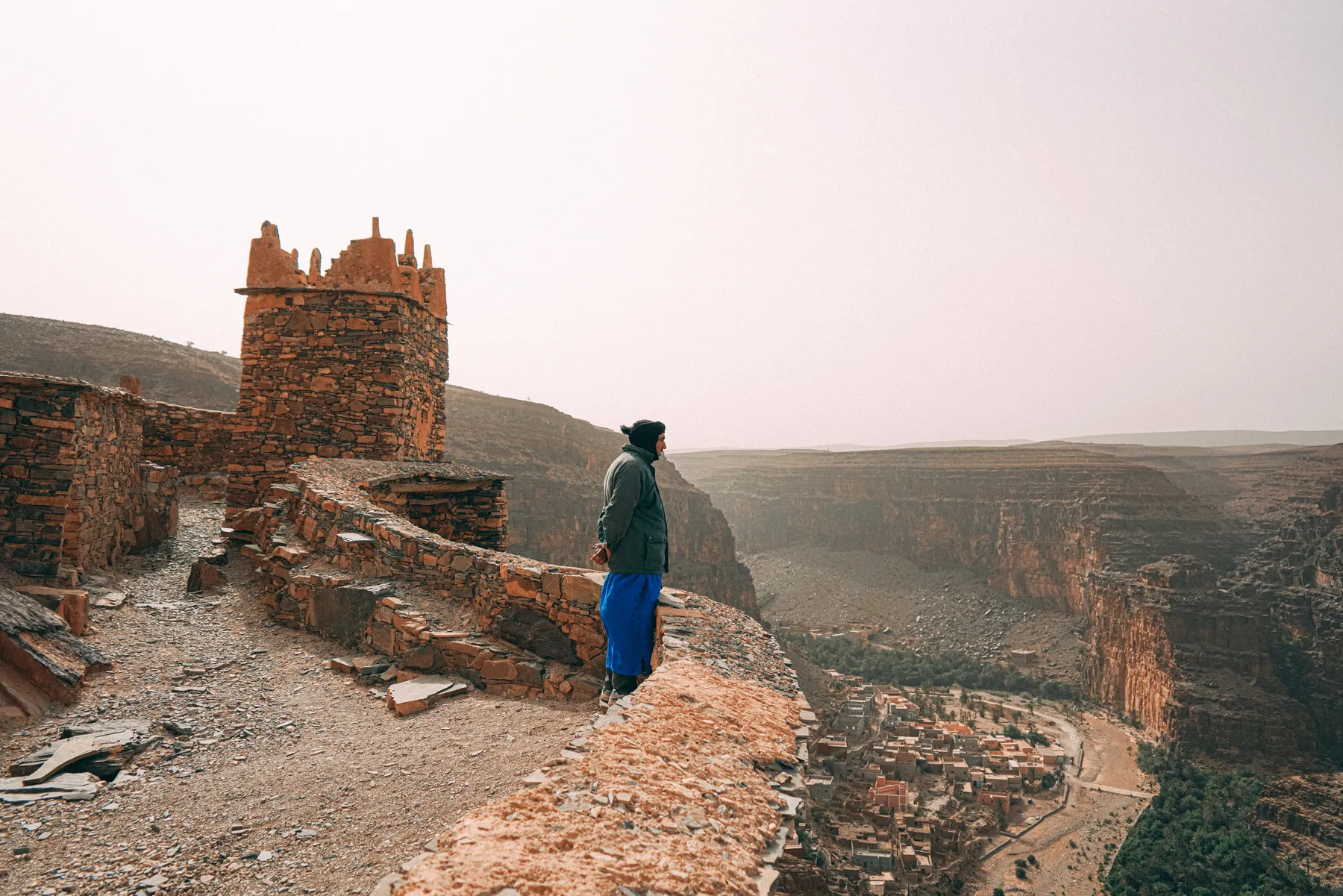 A guide in a blue robe looking over a canyon from an old granary
