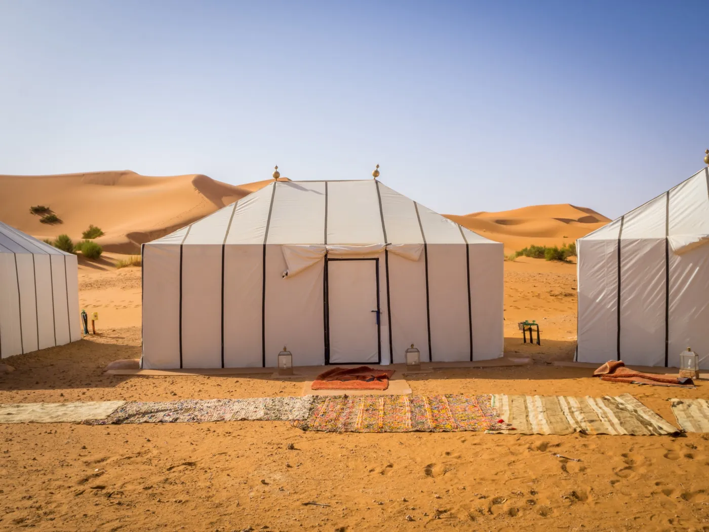 White Berber tents of a desert camp in front of the Erg Chebbi dunes